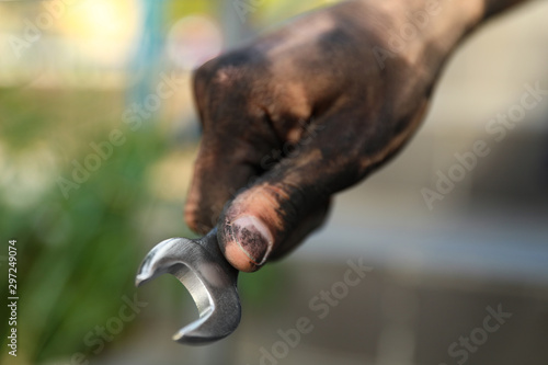 Dirty worker holding wrench on blurred background  closeup of hand