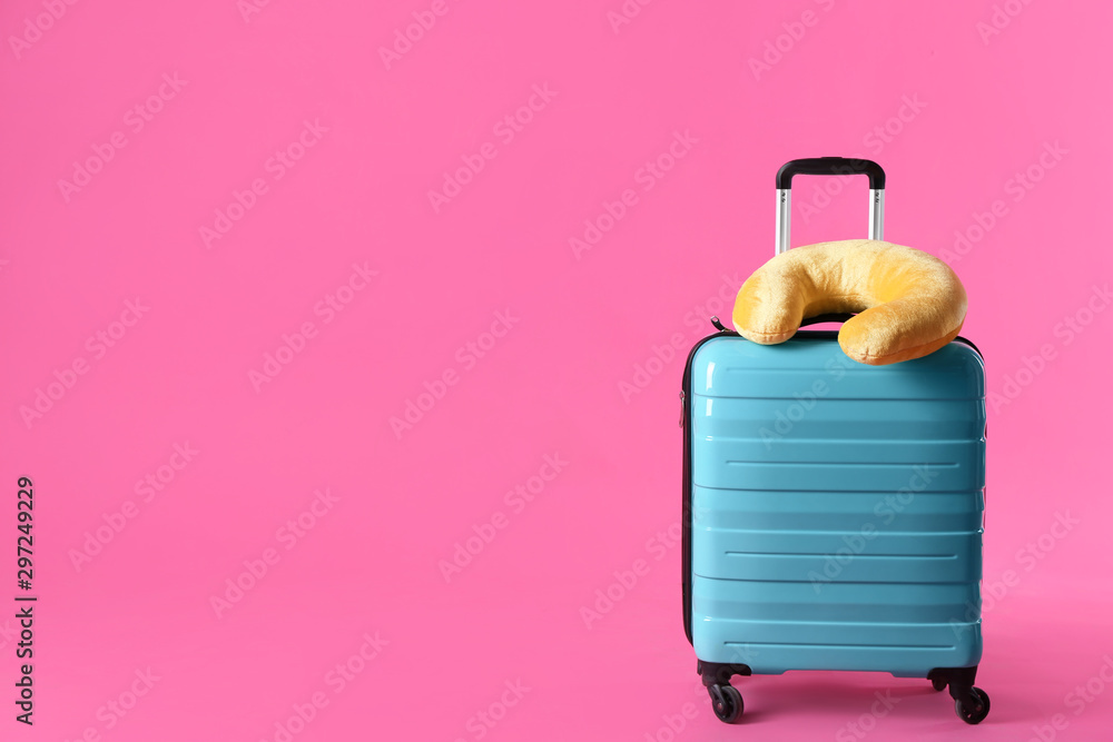 Turquoise suitcase and travel pillow on pink background, space for text - obrazy, fototapety, plakaty 