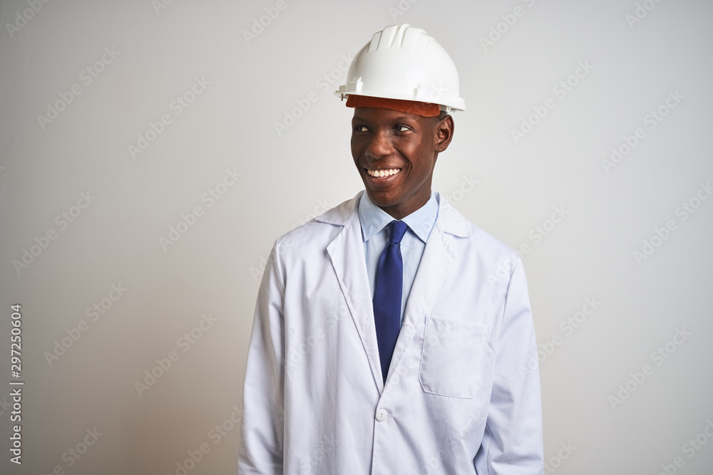 African american engineer man wearing coat and helmet over isolated white background looking away to side with smile on face, natural expression. Laughing confident.