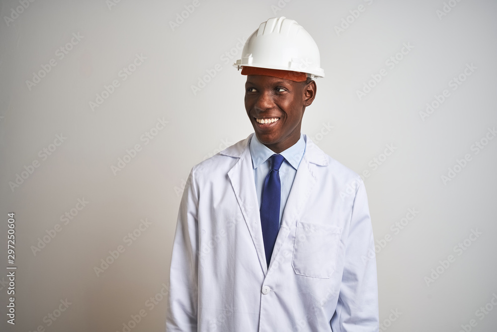 African american engineer man wearing coat and helmet over isolated white background looking away to side with smile on face, natural expression. Laughing confident. African american engineer man wearing coat and helmet over isolated white background looking away to side with smile on face, natural expression. Laughing confident.