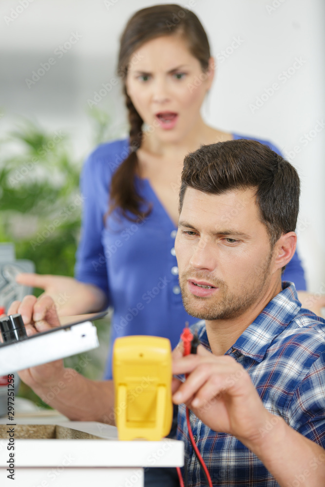 shocked woman looking at electrician technician measuring the voltage