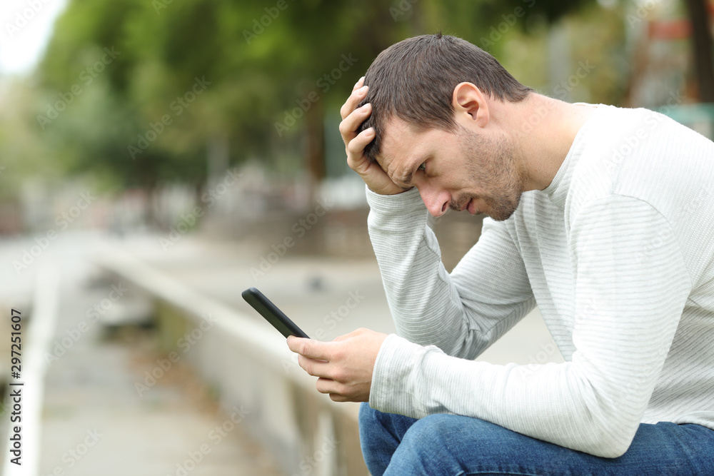 Sad man has bad online chat news and feels disappointed on the smartphone.  Stock Photo by ©sevendeman 506404148