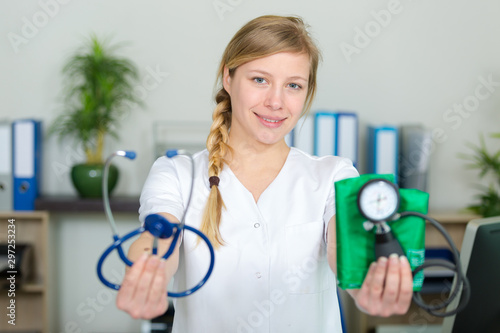 female doctor showing stethoscope and blood meassuring tool photo