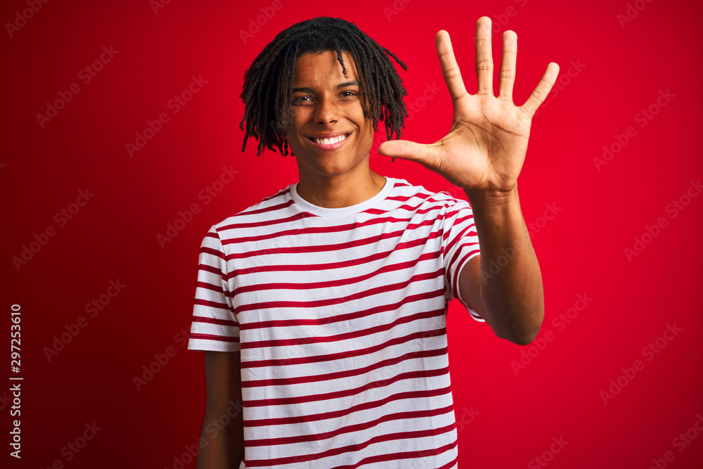 Young afro man with dreadlocks wearing striped t-shirt standing over isolated red background showing and pointing up with fingers number five while smiling confident and happy. Young afro man with dreadlocks wearing striped t-shirt standing over isolated red background showing and pointing up with fingers number five while smiling confident and happy.