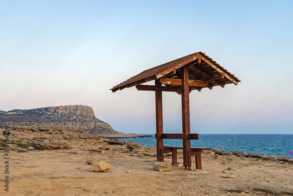 Romantic wooden bench overlooking the beautiful azure lagoon at sunset near Cape Greco. Cyprus. Romantic wooden bench overlooking the beautiful azure lagoon at sunset near Cape Greco. Cyprus.