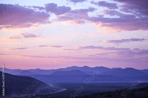 Panorama au couché du soleil de montagnes et ciel rose pale avec poussière de voiture au loin © Photos Eric Malherbe