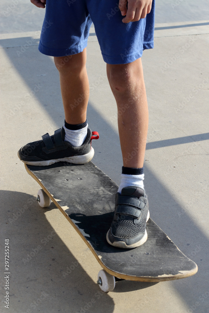 Feet of a kid who is standing on a skateboard in a skate park Feet of a kid who is standing on a skateboard in a skate park