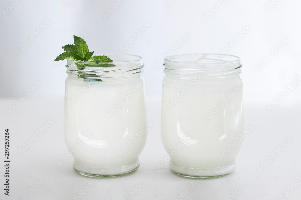 Organic probiotic milk kefir drink or yogurt in glass containers,on the white grey background. Gut health. Probiotic cold fermented dairy drink. Trendy food and drink. Copy space Organic probiotic milk kefir drink or yogurt in glass containers,on the white grey background. Gut health. Probiotic cold fermented dairy drink. Trendy food and drink. Copy space