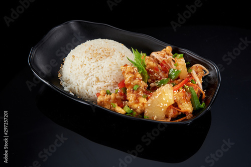 Steam rice and pork with pineapple on a black plate on a dark background