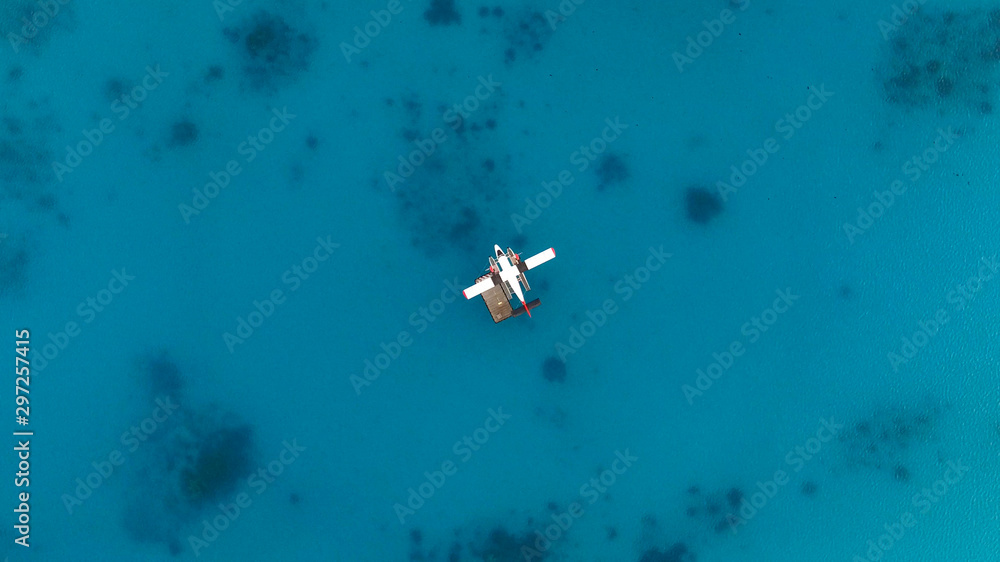 Aerial top view of seaplane isolated on water. White black red seaplane docked in the middle of the Maldivian lagoon of Indian Ocean, far away from Island. Concept; Travel agency, maldivian transport