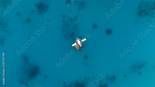 Aerial top view of seaplane isolated on water. White black red seaplane docked in the middle of the Maldivian lagoon of Indian Ocean, far away from Island. Concept; Travel agency, maldivian transport