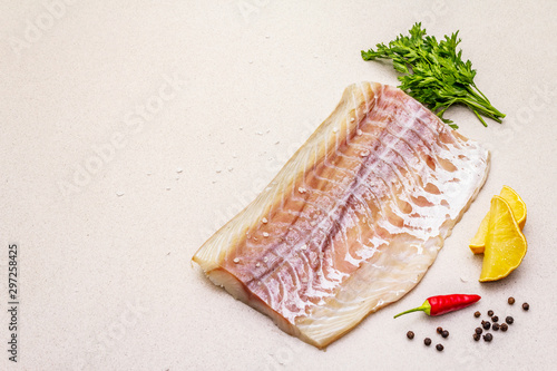 Raw pollock (Pollachius virens) fillet. Fresh fish for healthy food lifestyle. Lemon, parsley, sea salt, chili, black peppercorn
