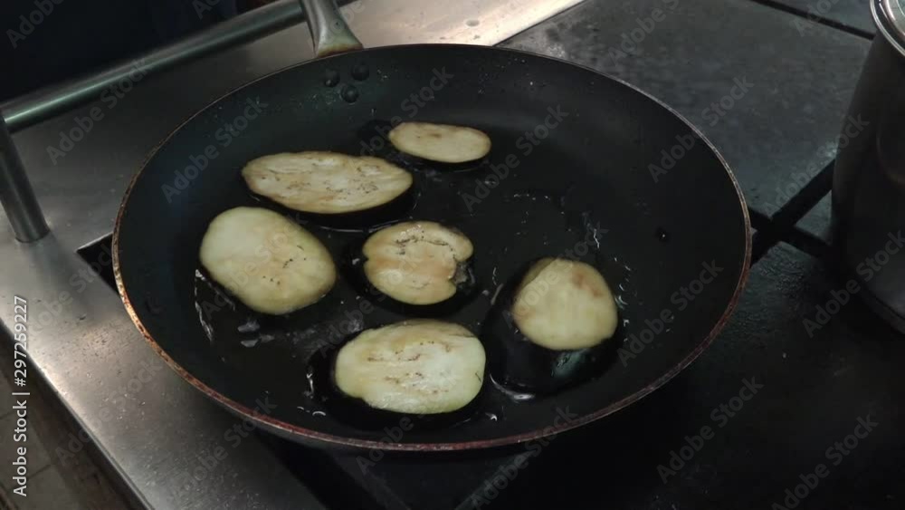 cook in white rubber gloves working on tanker Onyx fries aubergine slices on big pan in galley extreme close view cook in white rubber gloves working on tanker Onyx fries aubergine slices on big pan in galley extreme close view