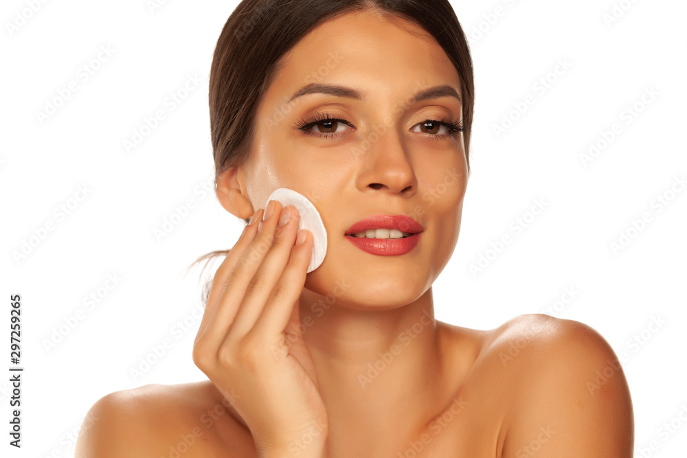 Young beautiful woman claning her face with cotton pad on white background Young beautiful woman claning her face with cotton pad on white background