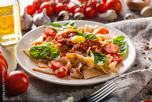 Fresh and simple homemade food. Plate of delicious pasta with tomatoes on the kitchen table. Close-up.