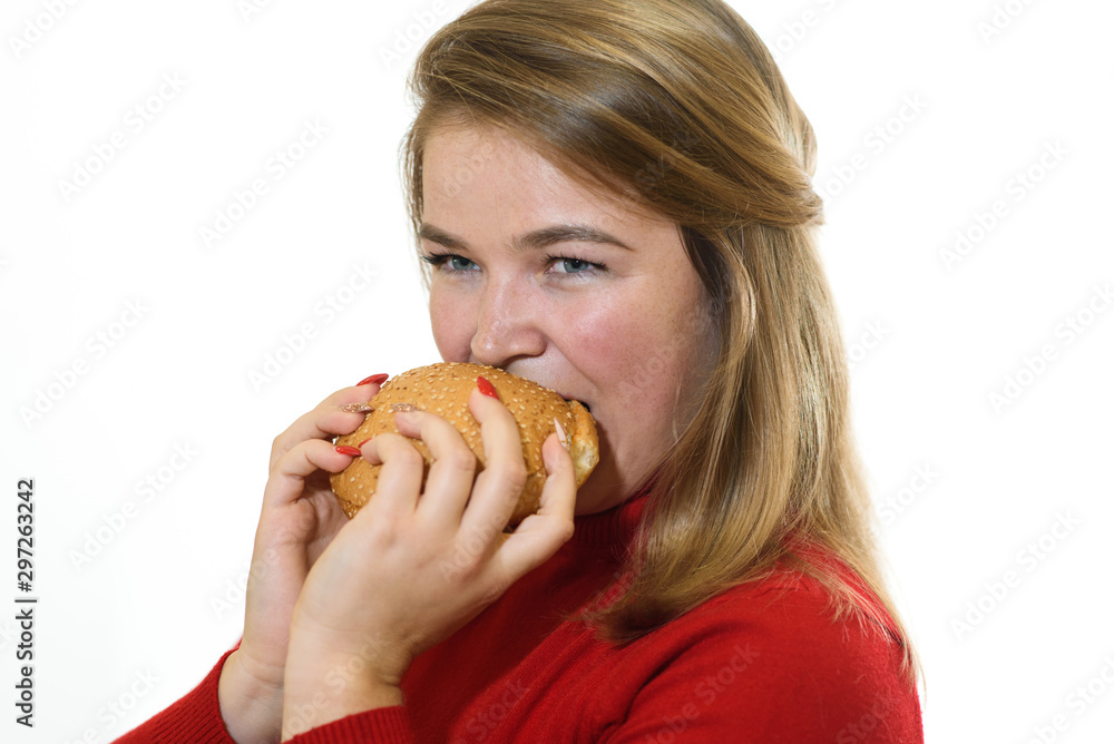 Young fat girl on a white background eats a burger. Studio shot Young fat girl on a white background eats a burger. Studio shot