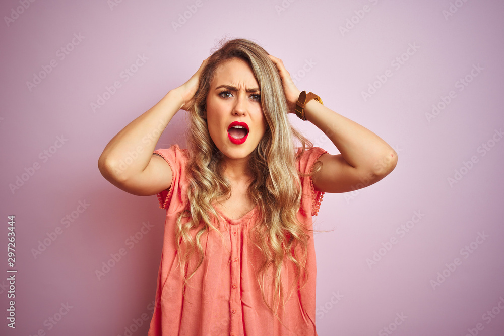 Young beautiful woman wearing t-shirt standing over pink isolated background Crazy and scared with hands on head, afraid and surprised of shock with open mouth Young beautiful woman wearing t-shirt standing over pink isolated background Crazy and scared with hands on head, afraid and surprised of shock with open mouth