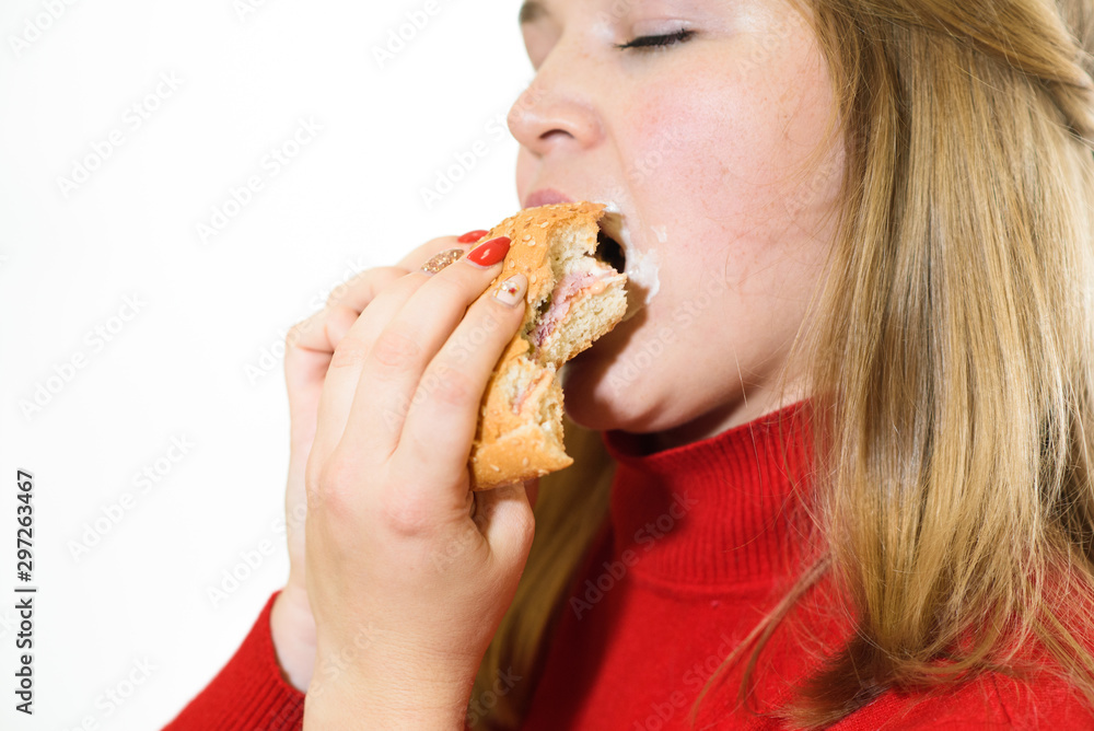 Young fat girl on a white background eats a burger. Studio shot