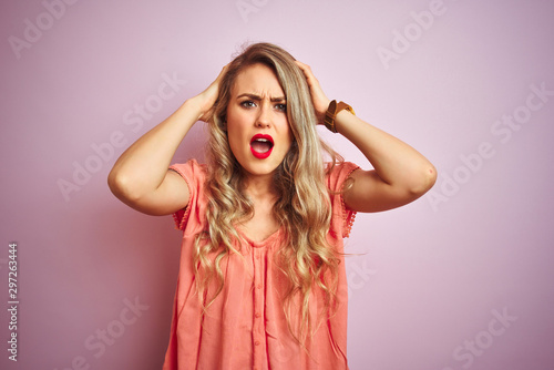 Young beautiful woman wearing t-shirt standing over pink isolated background Crazy and scared with hands on head, afraid and surprised of shock with open mouth