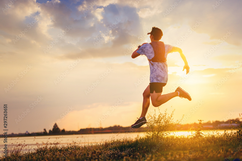 Silhouette of man trail run sprinting at river side. Fit male fitness runner during outdoor workout with sunset background Silhouette of man trail run sprinting at river side. Fit male fitness runner during outdoor workout with sunset background