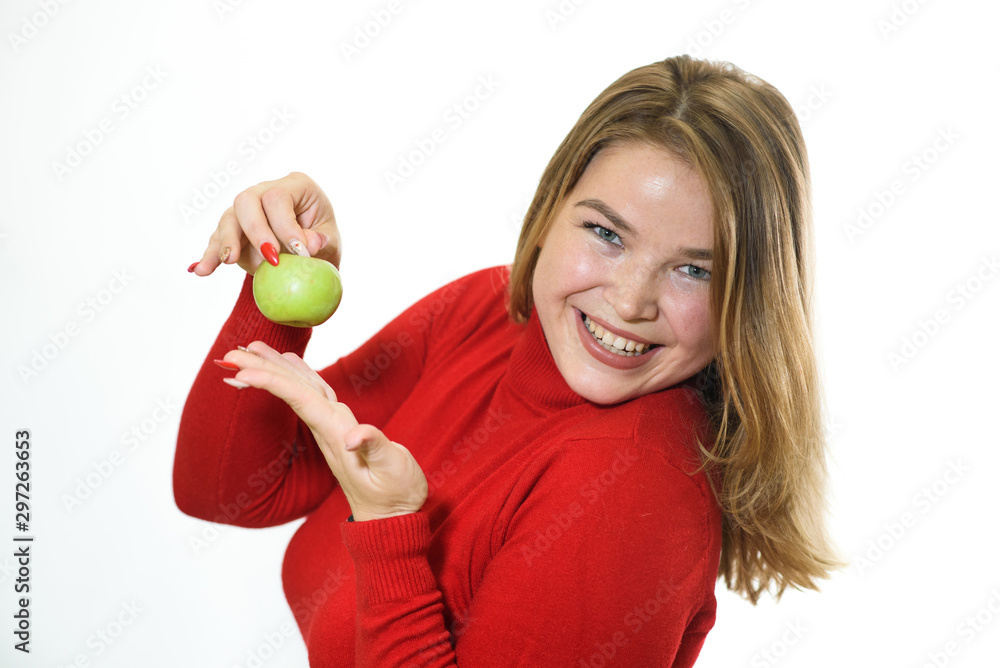 Fat girl on a white background rejoices to healthy food. Rejoices at the apple. Studio shot. Fat girl on a white background rejoices to healthy food. Rejoices at the apple. Studio shot.