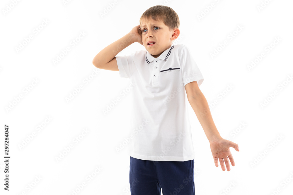 A little boy in a white shirt, blue shorts with blonde hair stands and is surprised A little boy in a white shirt, blue shorts with blonde hair stands and is surprised