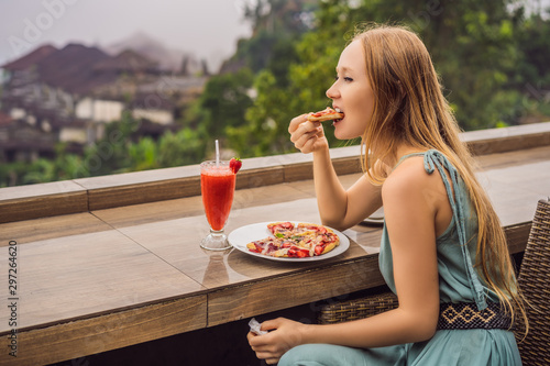 Woman eating delicious strawberry pizza on a balinese tropical nature background. Bali island, Indonesia photo