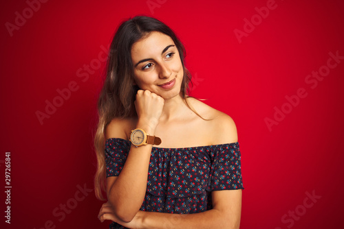 Young beautiful woman wearing a floral t-shirt over red isolated background with hand on chin thinking about question, pensive expression. Smiling with thoughtful face. Doubt concept.