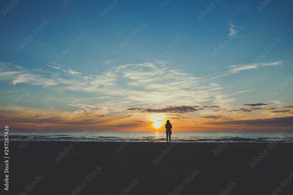 Aerial view woman silhouette standing by the sea and watching sunset 