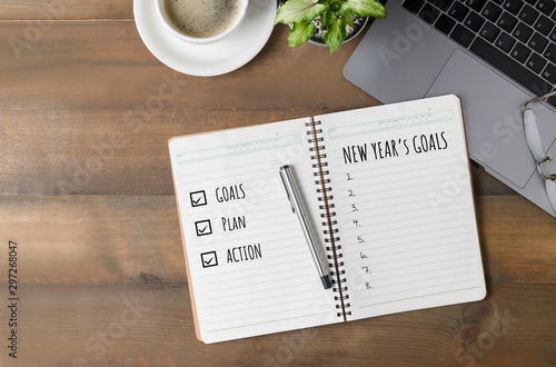 Hand man writing New year's goals on note paper photo