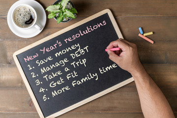 Hand man writing New year resolution on black board