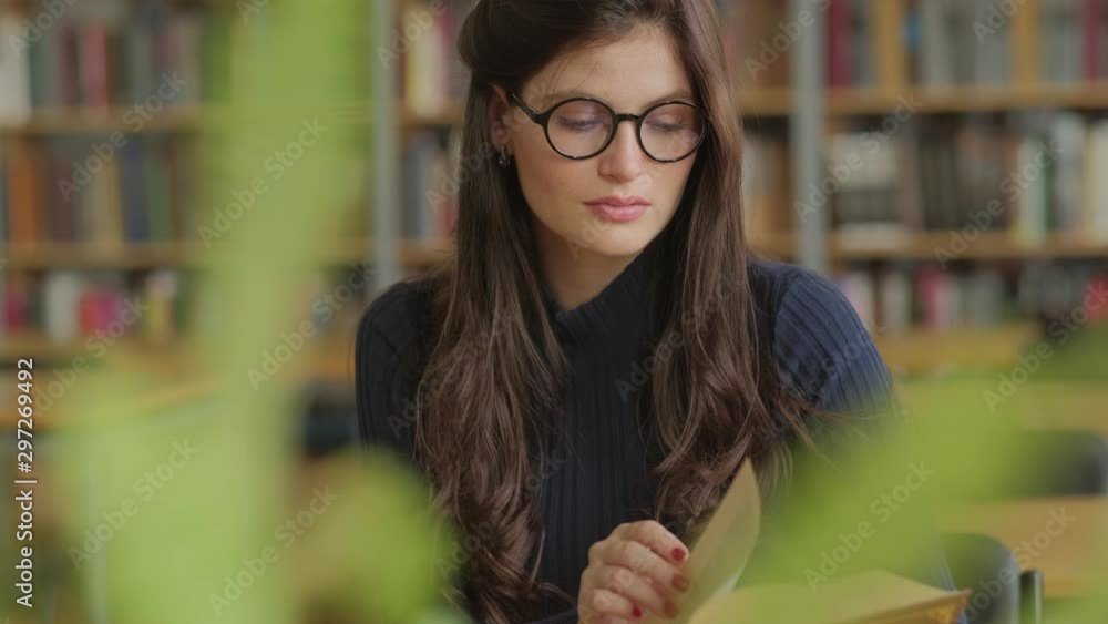 young, beautiful woman is reading a book in a library. Student and learning concept. young, beautiful woman is reading a book in a library. Student and learning concept.