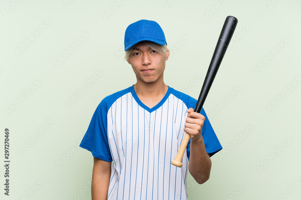 Fototapeta premium Young asian man playing baseball over isolated green background with sad expression