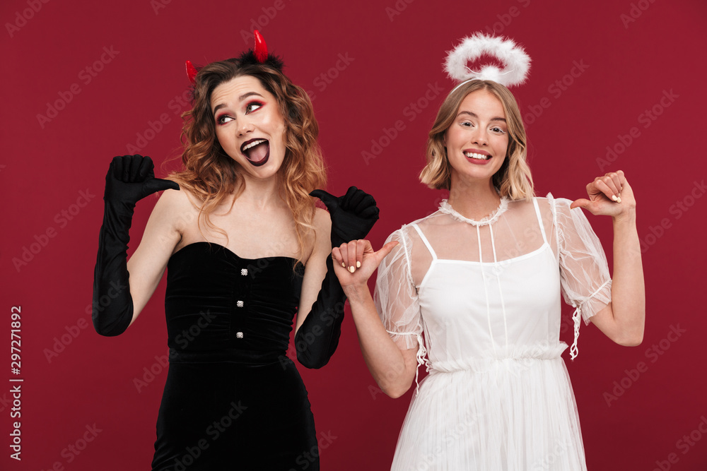 Demon and angel in carnival costumes pointing to themselves. Demon and angel in carnival costumes pointing to themselves.