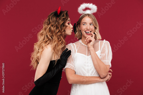 Demon and angel in carnival costumes gossiping.