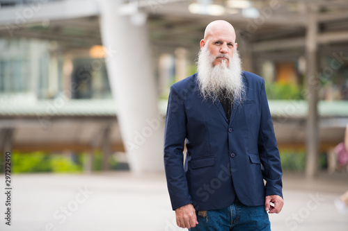 Mature bearded bald businessman in the city outdoors photo