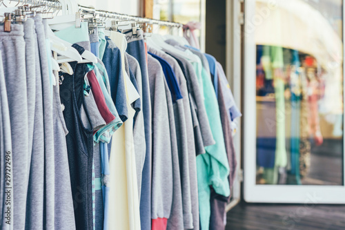 In the showroom, simple cotton clothes hang in a row on hangers.