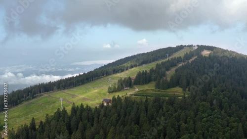 Aerial circle pan of Kope ski slope and a lake in dense pine forest in Slovenia