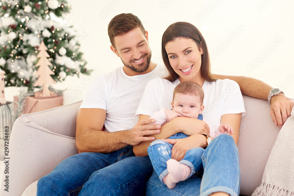 Lovely family with their baby girls relaxing on sofa at home