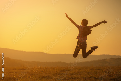 Happy child jumping in nature in sunset.