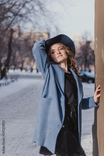 Outdoor portrait of young beautiful fashionable woman posing in street. Model wearing stylish  coat, hat. Female fashion concept, city lifestyle.hat in retro style, fashion trends in the cold season.