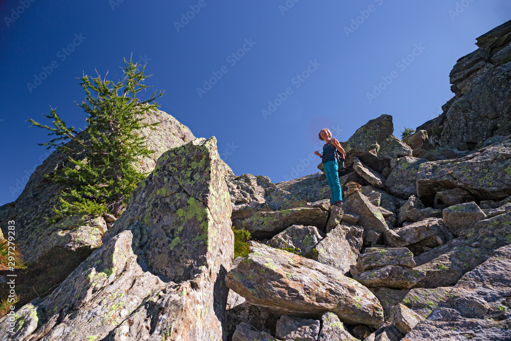 A hiker walking on the mountain path on a sunny autumn day.