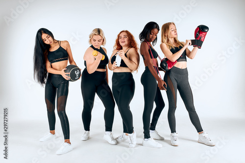 Young different girls doing sport exercises isolated over white background, using sportive things, dumbbells, boxing gloves. Healthy lifestyle, sport concept
