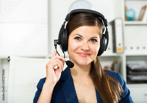 Smiling young female operator talking with customer using headset at company office
