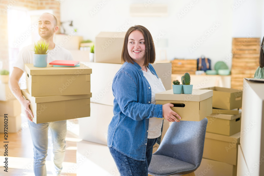 Young couple moving to a new home, smiling happy holding cardboard boxes Young couple moving to a new home, smiling happy holding cardboard boxes