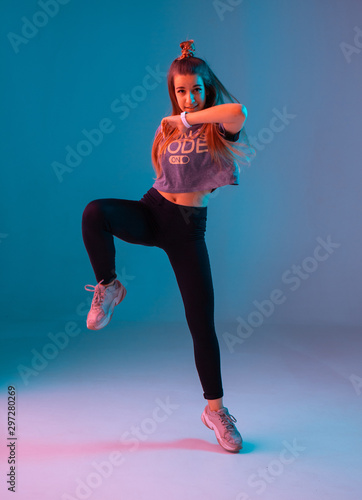 Young stylish girl dancing zumba in the Studio on a colored neon background. Dance poster design. photo