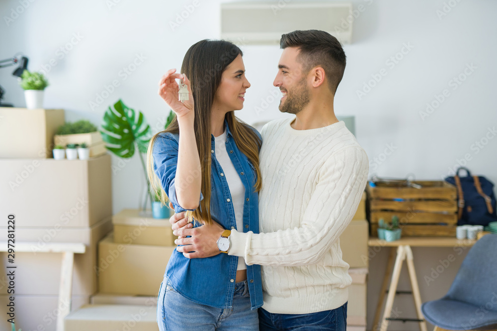 Young couple moving to a new home, hugging in love showing keys of new apartment smiling very happy Young couple moving to a new home, hugging in love showing keys of new apartment smiling very happy