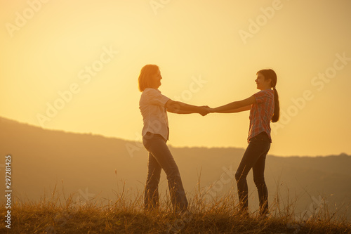 Happy family enjoying sunset. Grandmother and granddaughter holding hands.