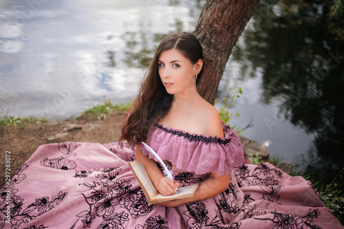 Εκτύπωση καμβά A beautiful young woman in a 19th-century dress sits by a pond and writes with a quill pen in a book, a portrait