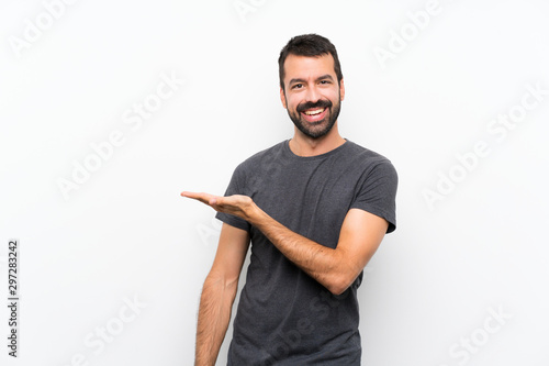 Young handsome man over isolated white background presenting an idea while looking smiling towards photo